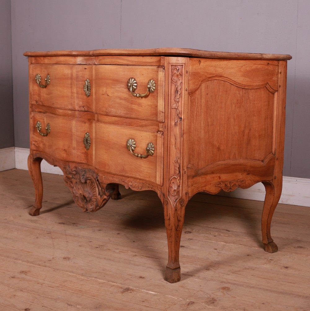 An eighteenth-century French serpentine timber chest of drawers featuring two drawer fronts, brass handles, and a centrally carved shell apron. View II