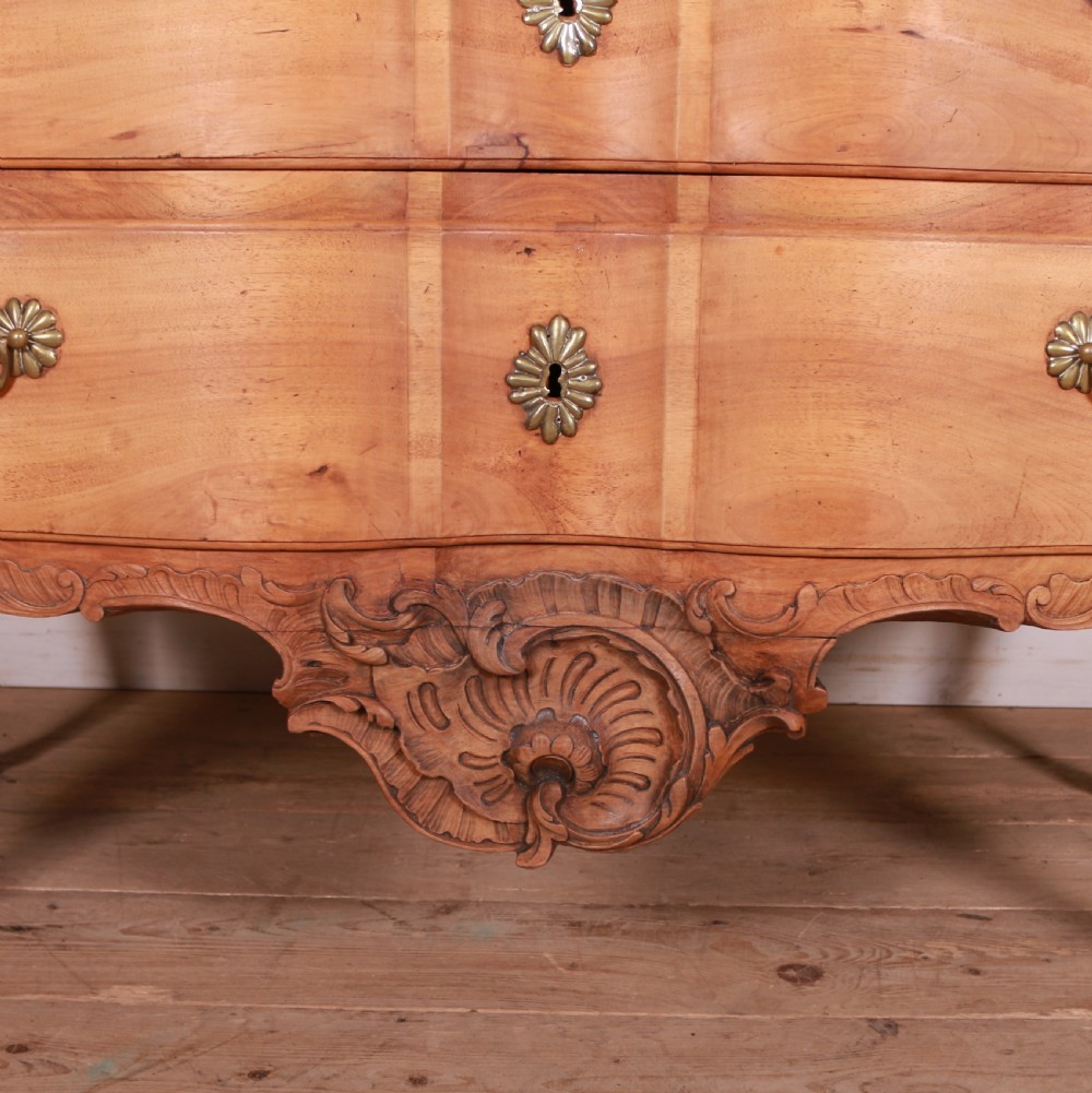 An eighteenth-century French serpentine timber chest of drawers featuring two drawer fronts, brass handles, and a centrally carved shell apron. View IV
