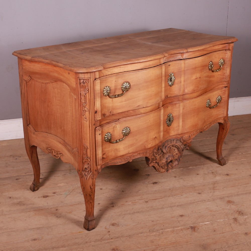 An eighteenth-century French serpentine timber chest of drawers featuring two drawer fronts, brass handles, and a centrally carved shell apron. View VII