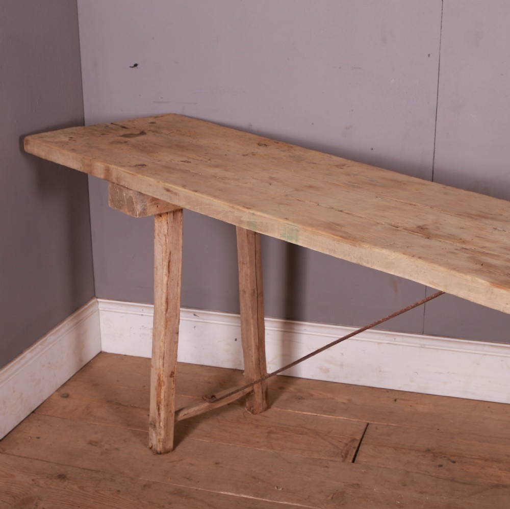 An elongated antique French trestle table made of scrubbed pale poplar wood with rustic A-frame legs and diagonal metal stretchers. View II