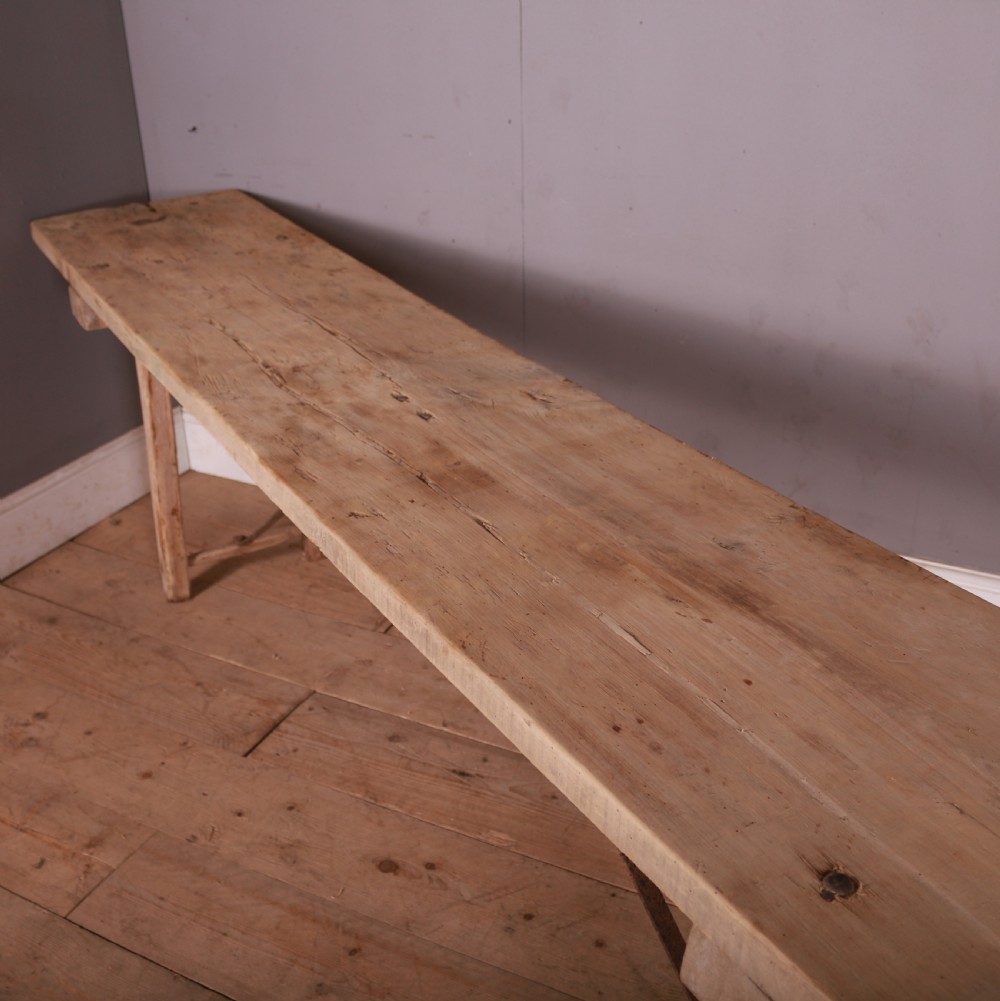 An elongated antique French trestle table made of scrubbed pale poplar wood with rustic A-frame legs and diagonal metal stretchers. View IV
