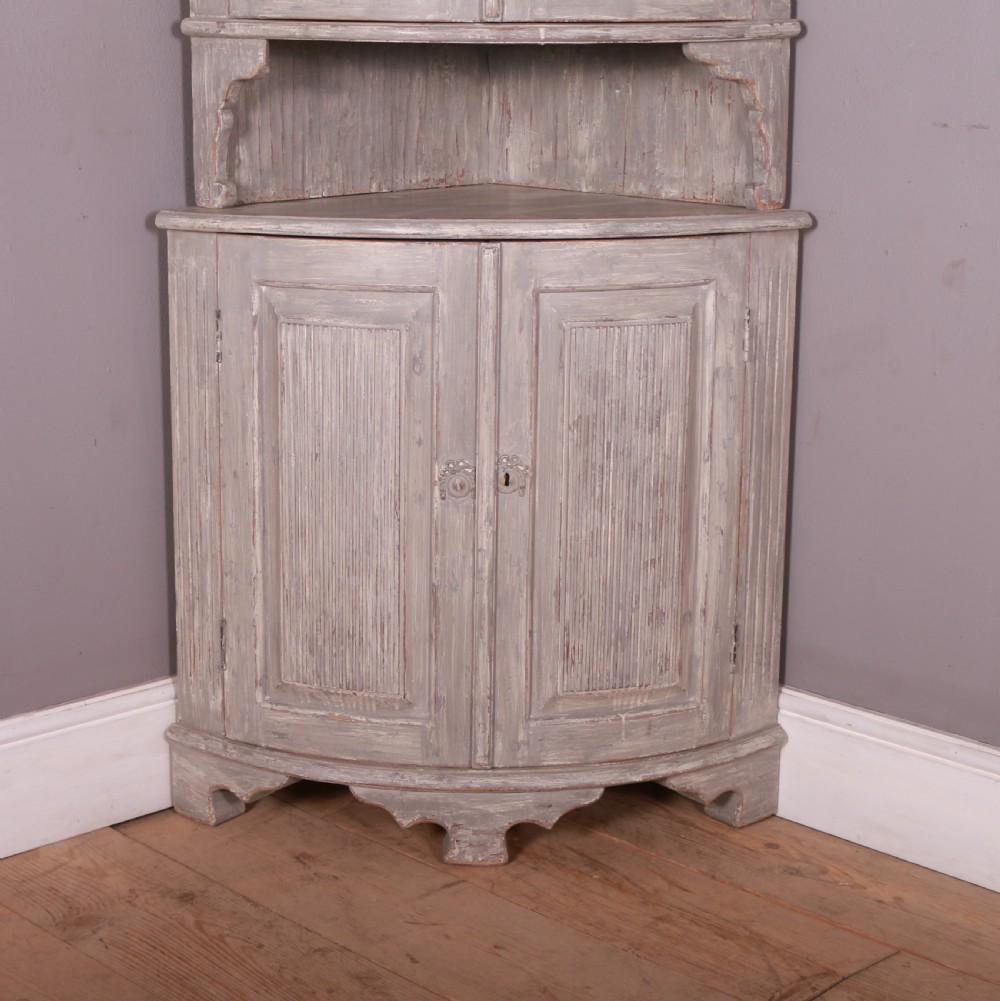 A tall antique Swedish bowfronted corner cupboard with a weathered grey painted finish, featuring panelled upper and lower doors and an open central niche. View III