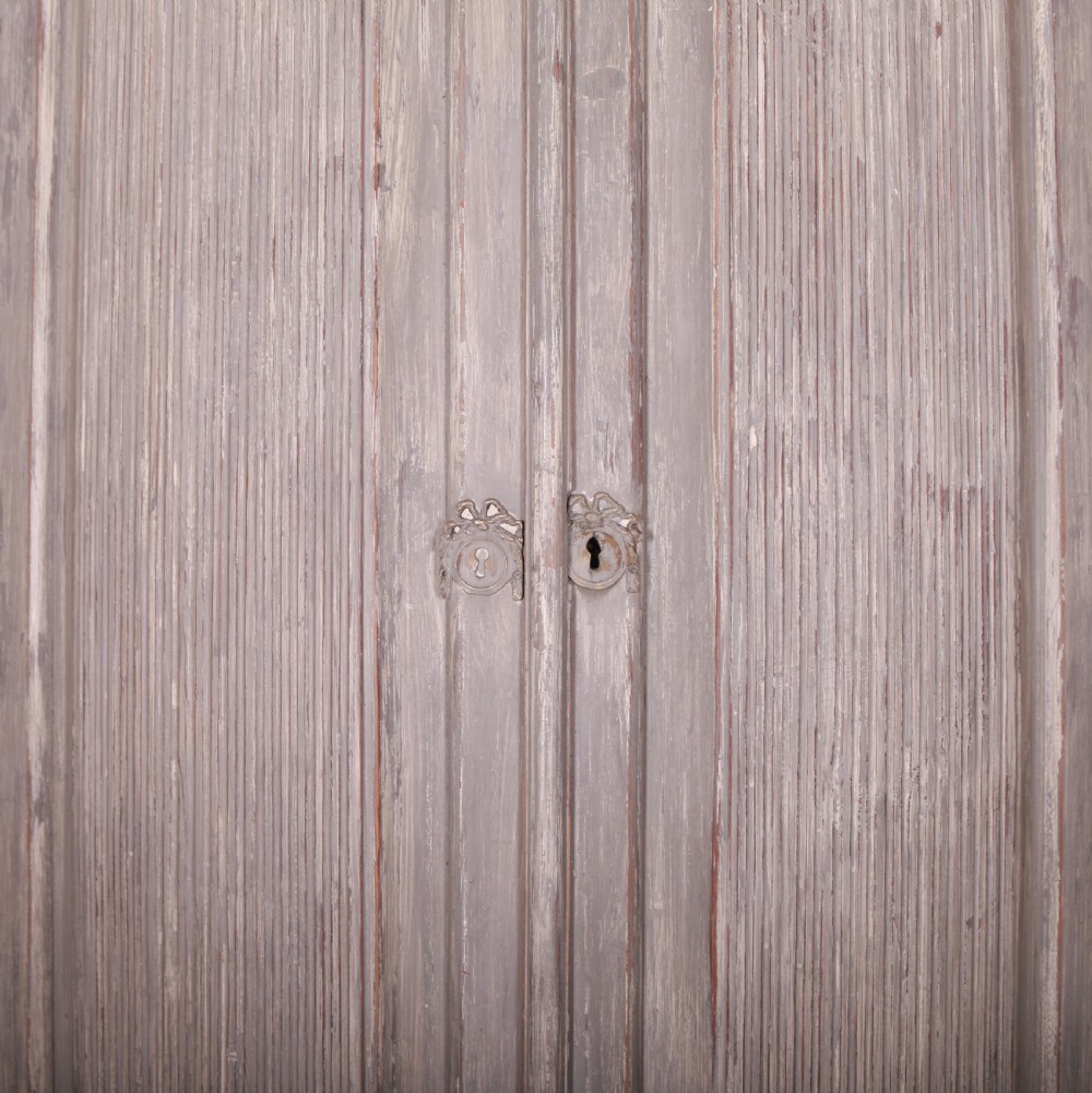 A tall antique Swedish bowfronted corner cupboard with a weathered grey painted finish, featuring panelled upper and lower doors and an open central niche. View VI