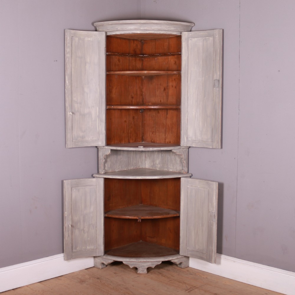 A tall antique Swedish bowfronted corner cupboard with a weathered grey painted finish, featuring panelled upper and lower doors and an open central niche. View VII
