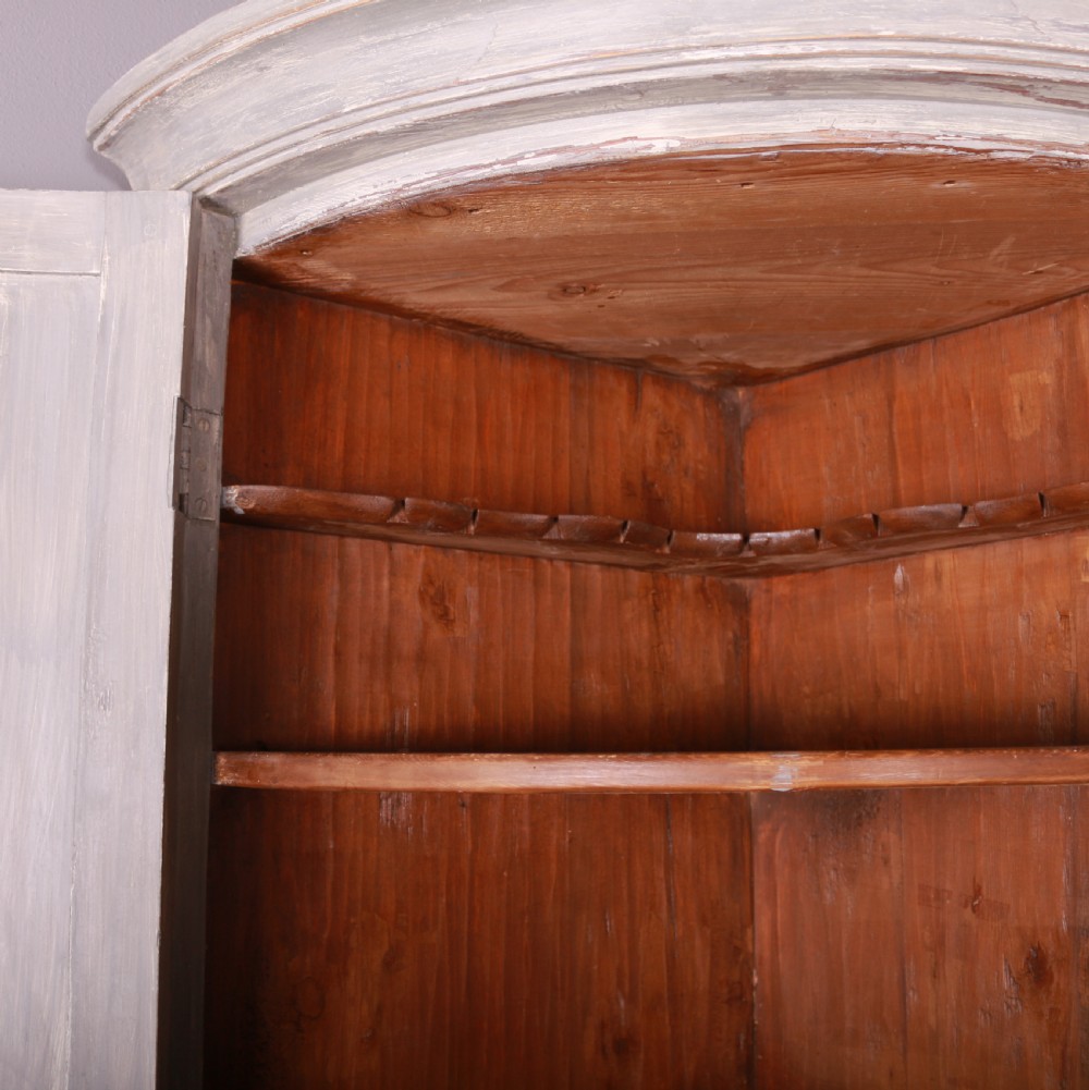 A tall antique Swedish bowfronted corner cupboard with a weathered grey painted finish, featuring panelled upper and lower doors and an open central niche. View VIII