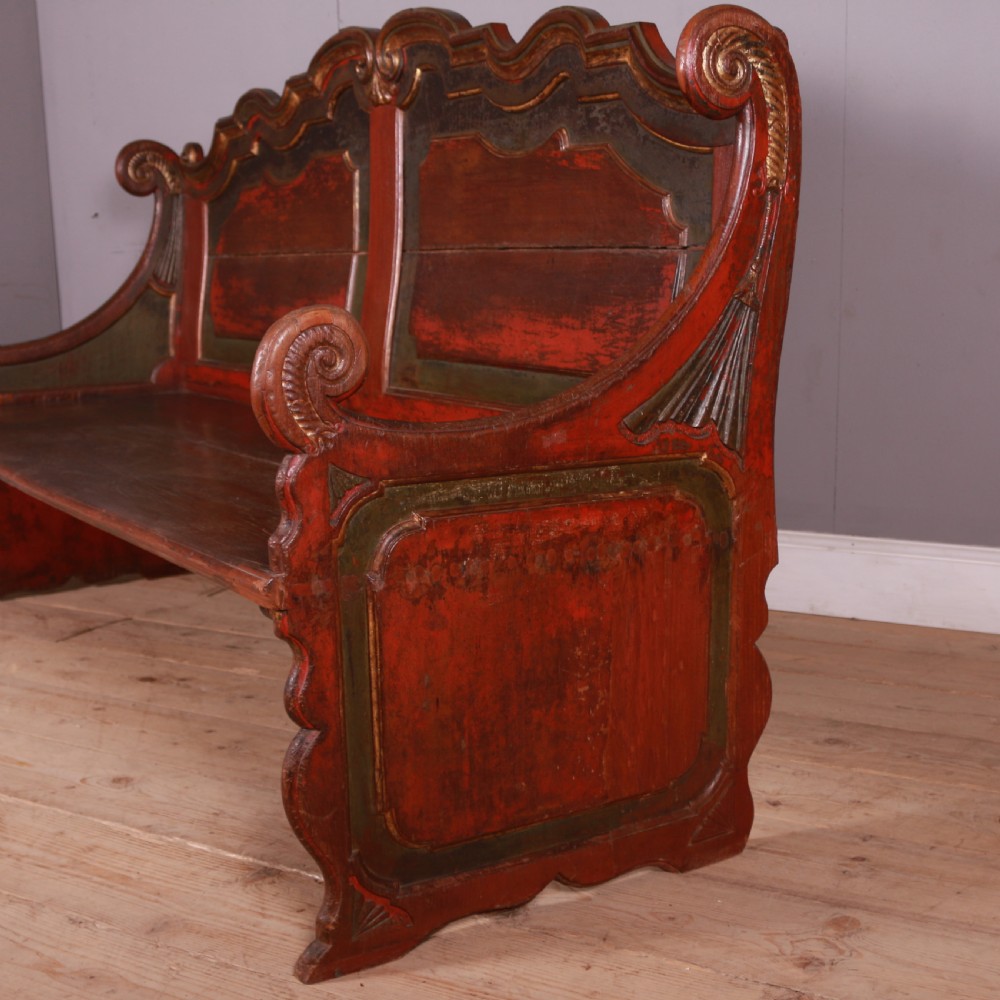An 18th-century Dutch painted wooden bench with a high serpentine back, scrolled arms, and red and dark green polychrome decoration. View II