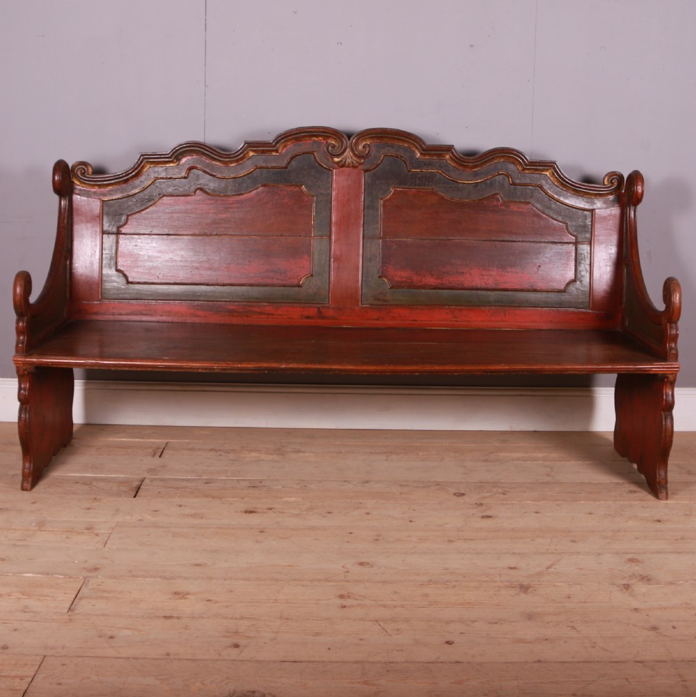 An 18th-century Dutch painted wooden bench with a high serpentine back, scrolled arms, and red and dark green polychrome decoration. View IV