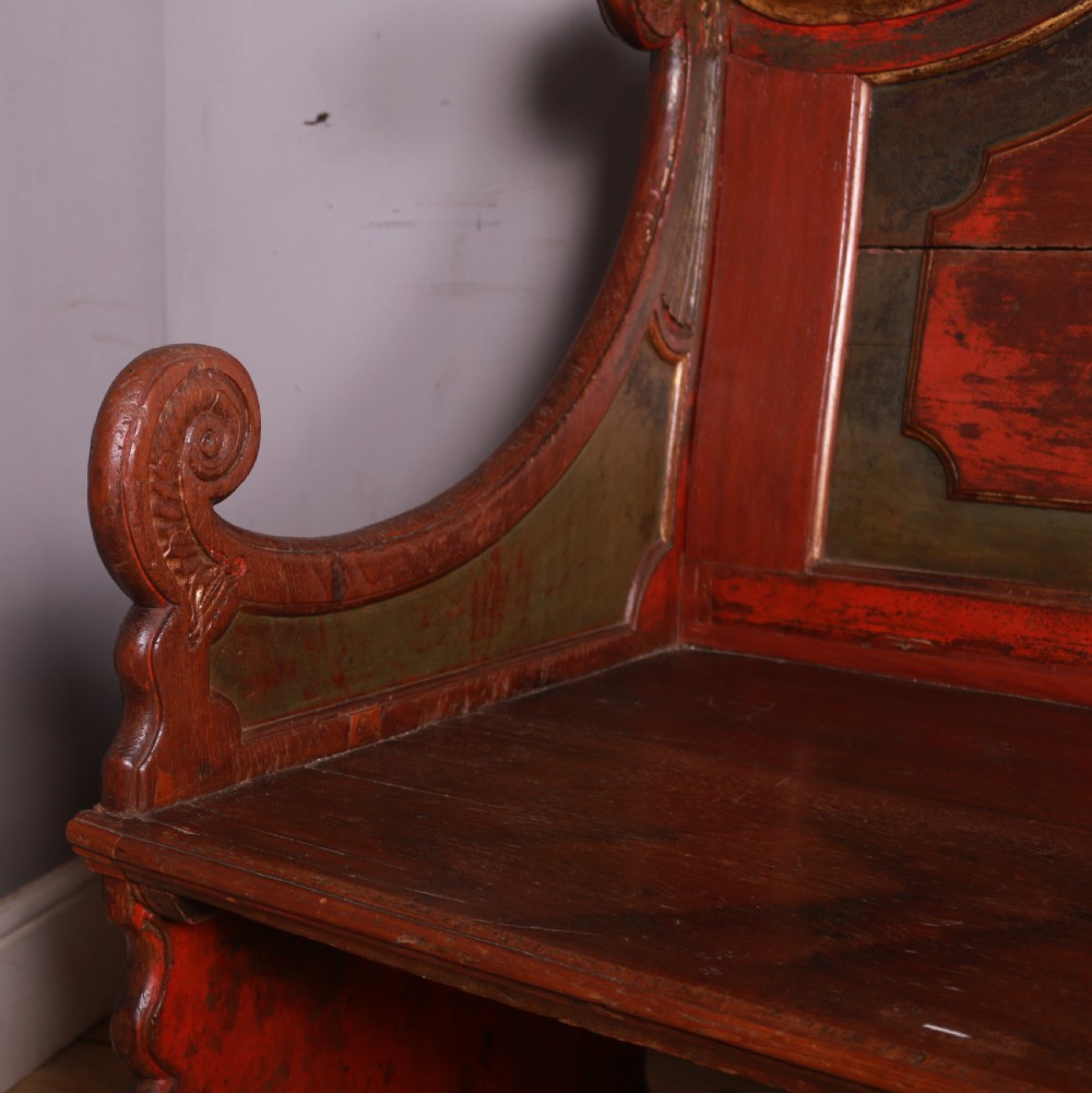 An 18th-century Dutch painted wooden bench with a high serpentine back, scrolled arms, and red and dark green polychrome decoration. View VI