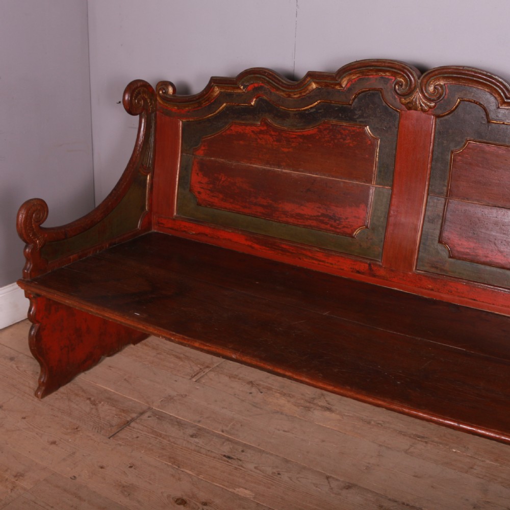 An 18th-century Dutch painted wooden bench with a high serpentine back, scrolled arms, and red and dark green polychrome decoration. View VII