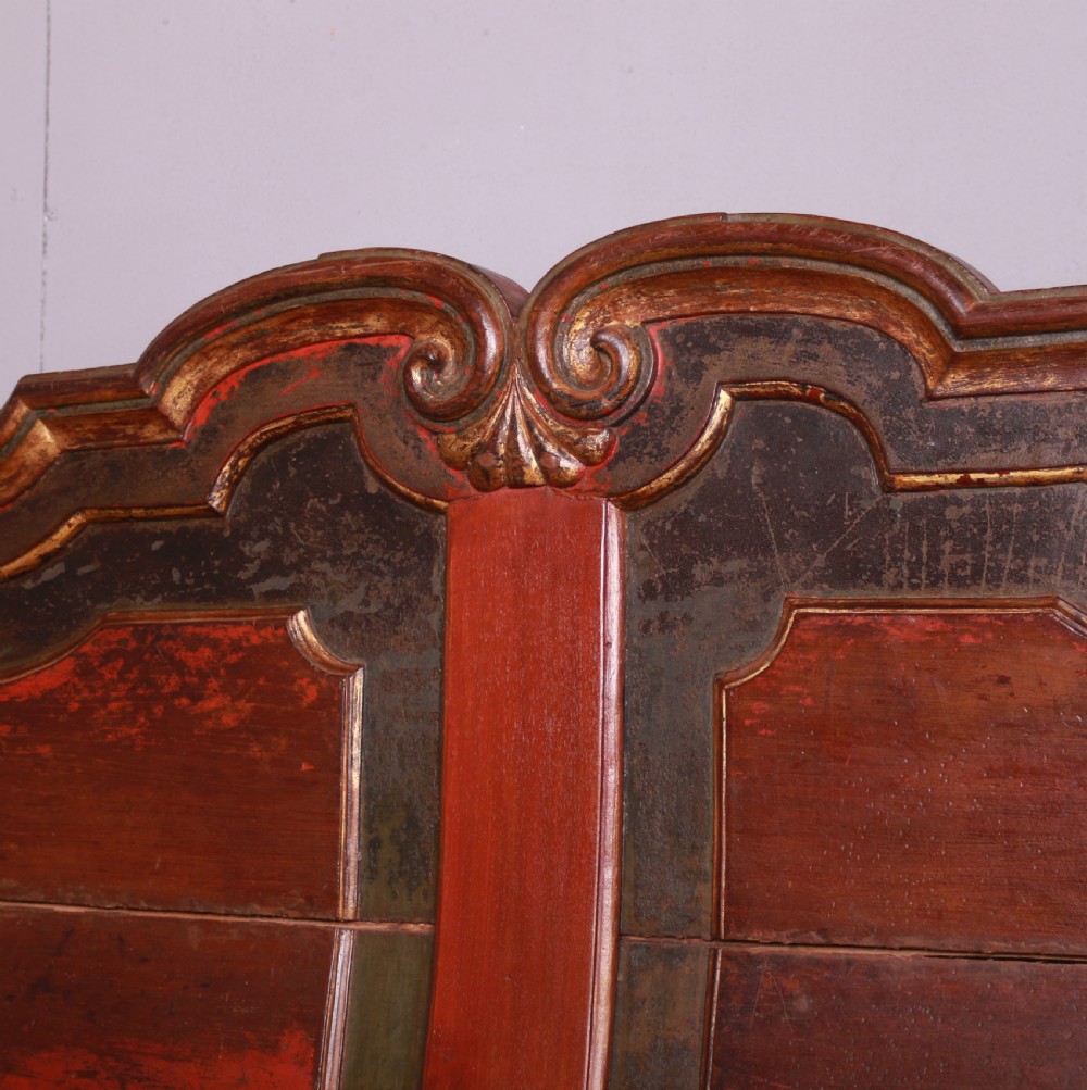 An 18th-century Dutch painted wooden bench with a high serpentine back, scrolled arms, and red and dark green polychrome decoration. View IX