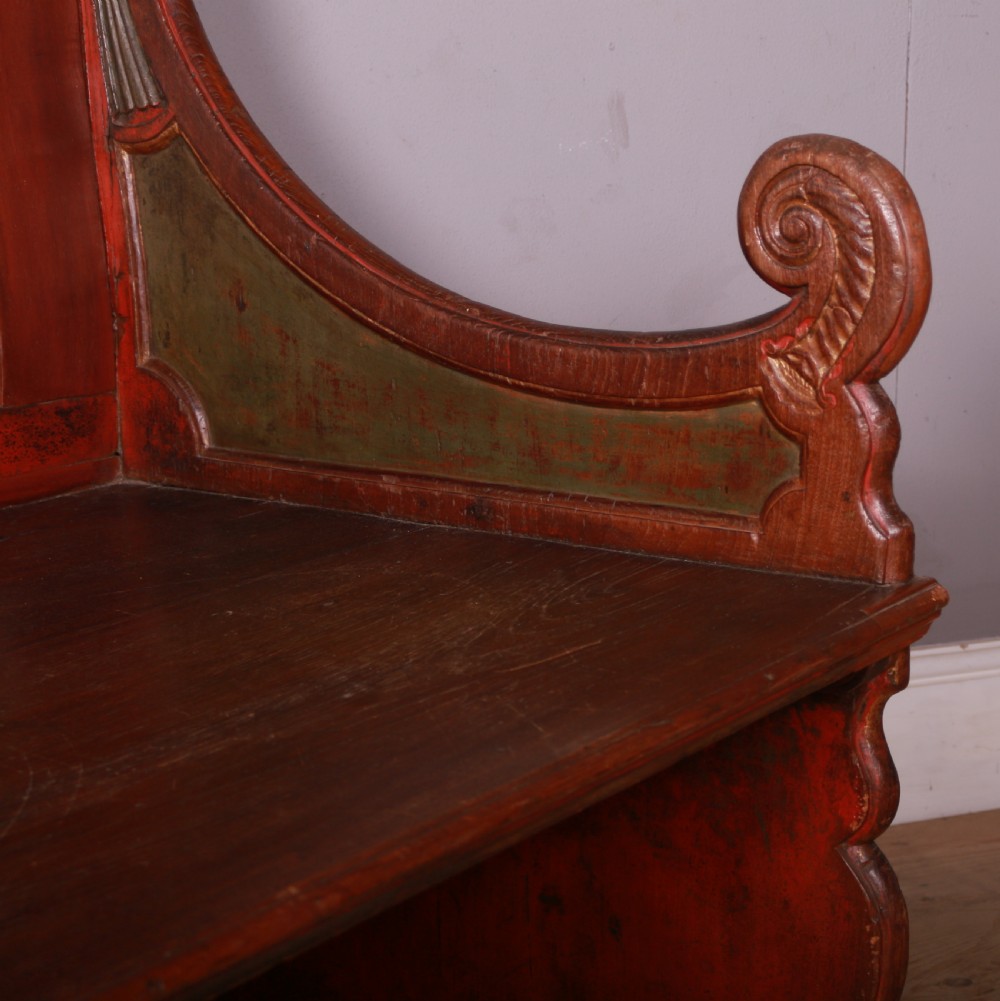 An 18th-century Dutch painted wooden bench with a high serpentine back, scrolled arms, and red and dark green polychrome decoration. View X