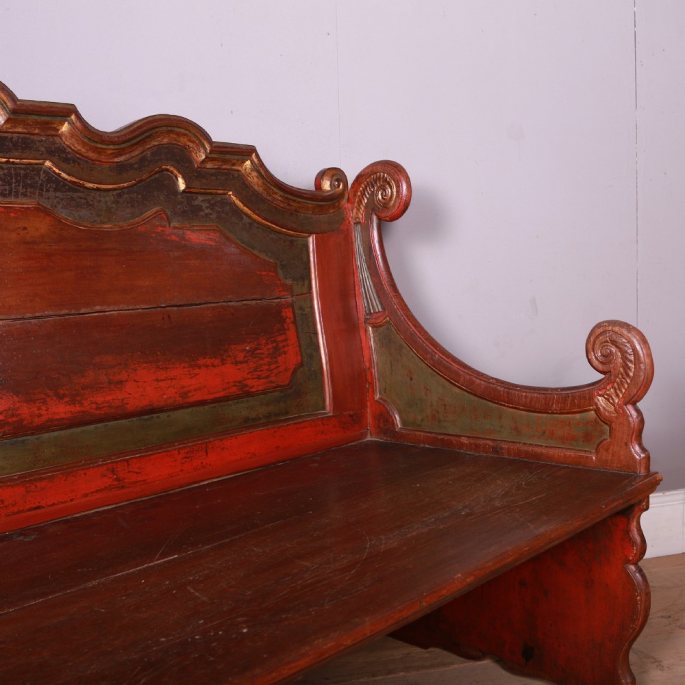 An 18th-century Dutch painted wooden bench with a high serpentine back, scrolled arms, and red and dark green polychrome decoration. View XI