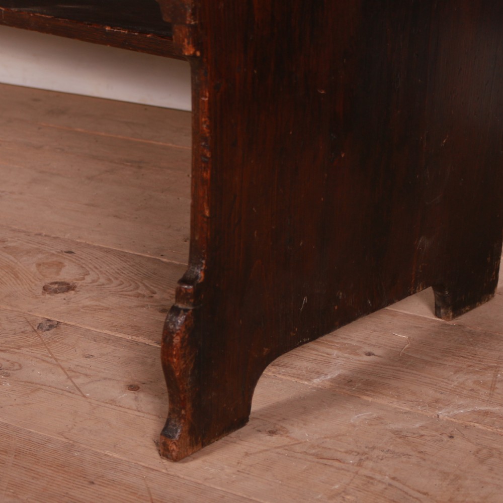 A dark-stained pine dresser base featuring three drawers with brass handles above an arched apron and an open potboard shelf. View II