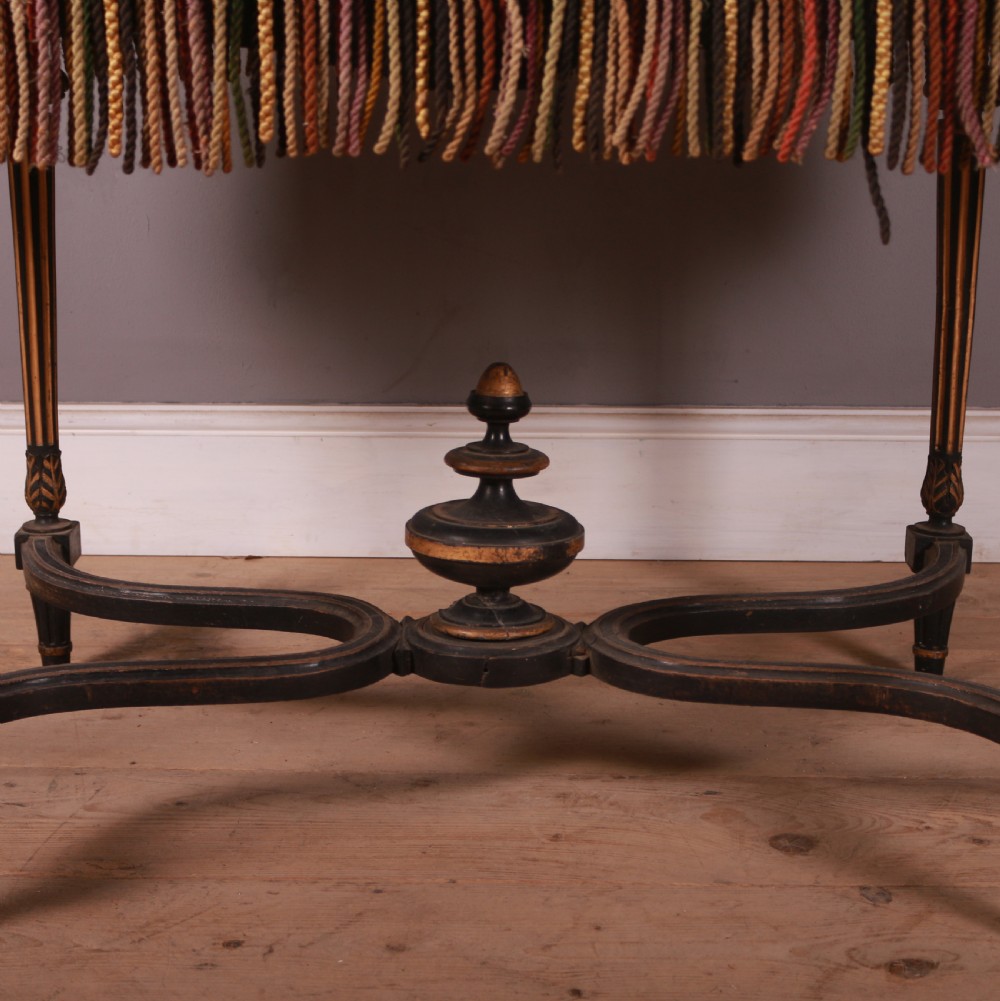 A 19th-century French ebonised centre table featuring fluted legs with gilt accents, a curved stretcher with a turned finial, and a floral tapestry top surrounded by long fringe. View III