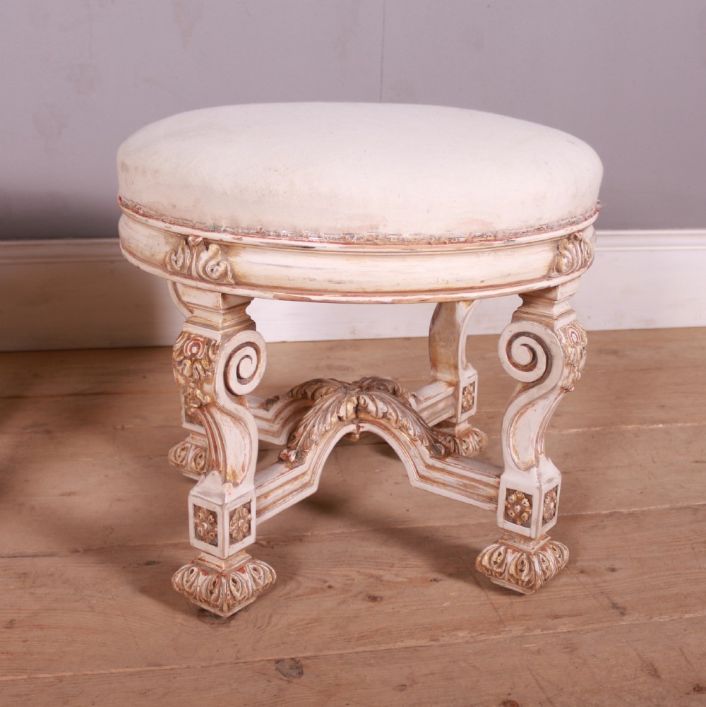 A pair of circular Swedish stools featuring cream and gold painted frames, scroll legs, arched stretchers, and off-white upholstered seats. View III