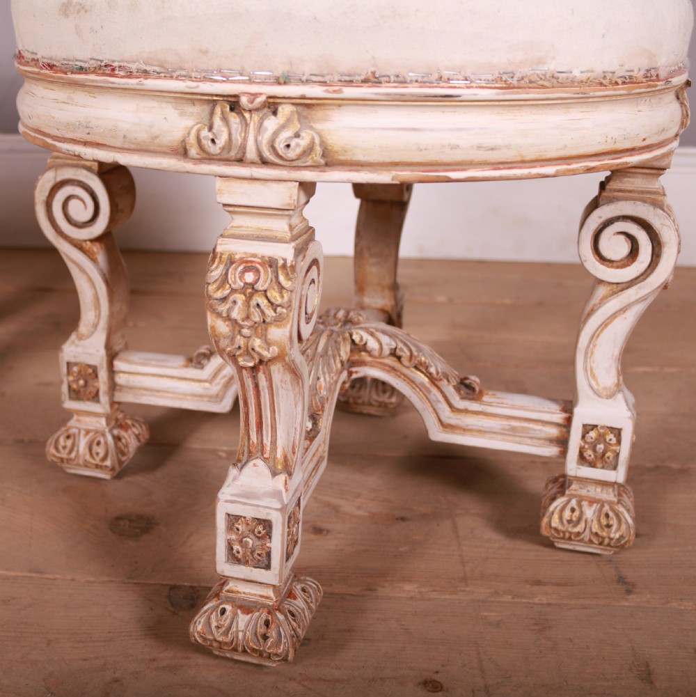 A pair of circular Swedish stools featuring cream and gold painted frames, scroll legs, arched stretchers, and off-white upholstered seats. View IV