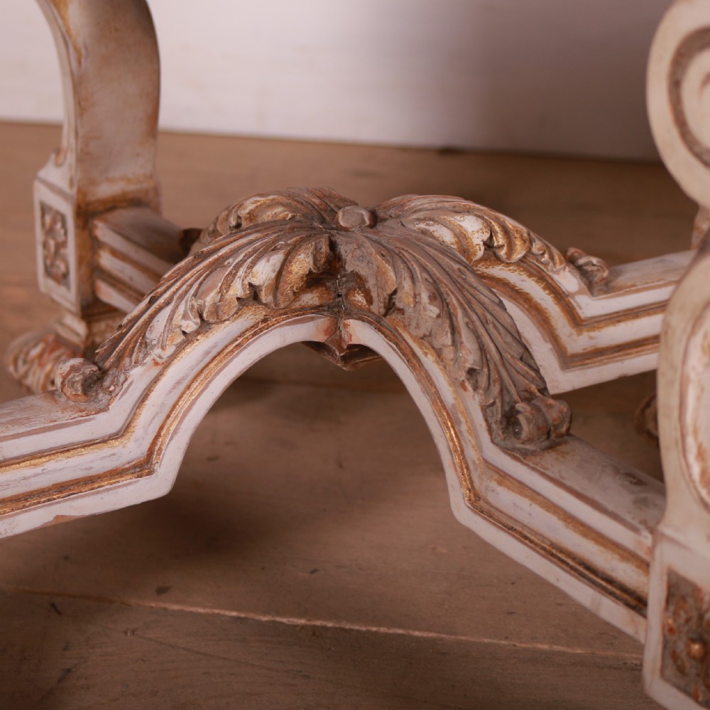 A pair of circular Swedish stools featuring cream and gold painted frames, scroll legs, arched stretchers, and off-white upholstered seats. View V