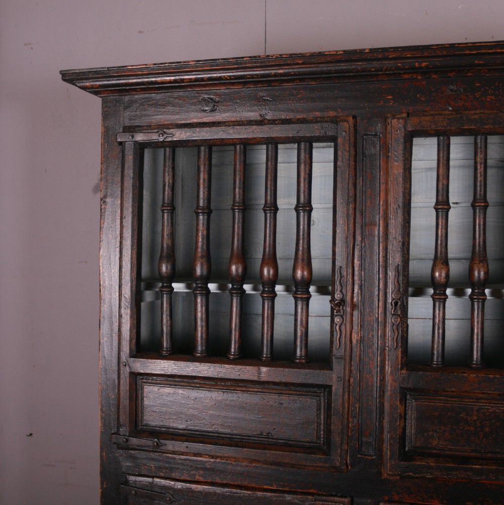An 18th-century French dark oak food cupboard featuring turned spindle upper door panels and solid wooden lower door panels. View IV