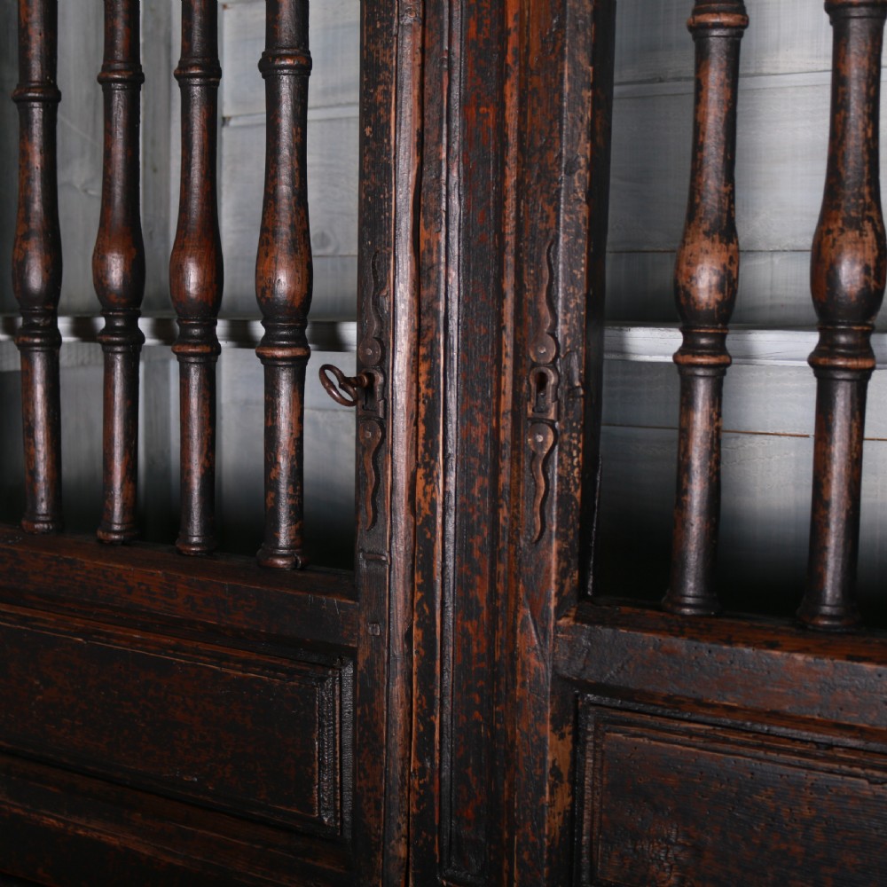 An 18th-century French dark oak food cupboard featuring turned spindle upper door panels and solid wooden lower door panels. View VI