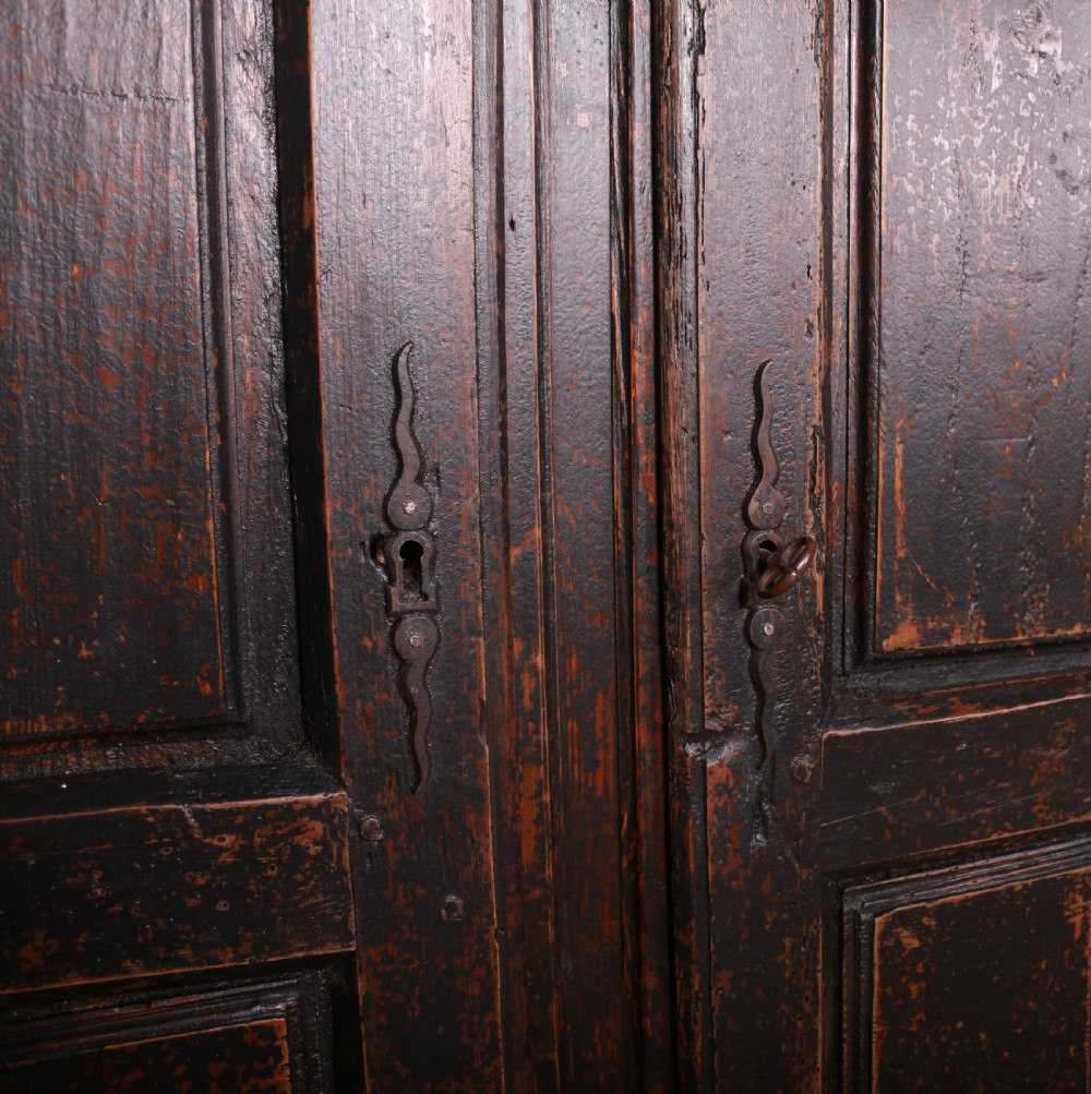 An 18th-century French dark oak food cupboard featuring turned spindle upper door panels and solid wooden lower door panels. View VII