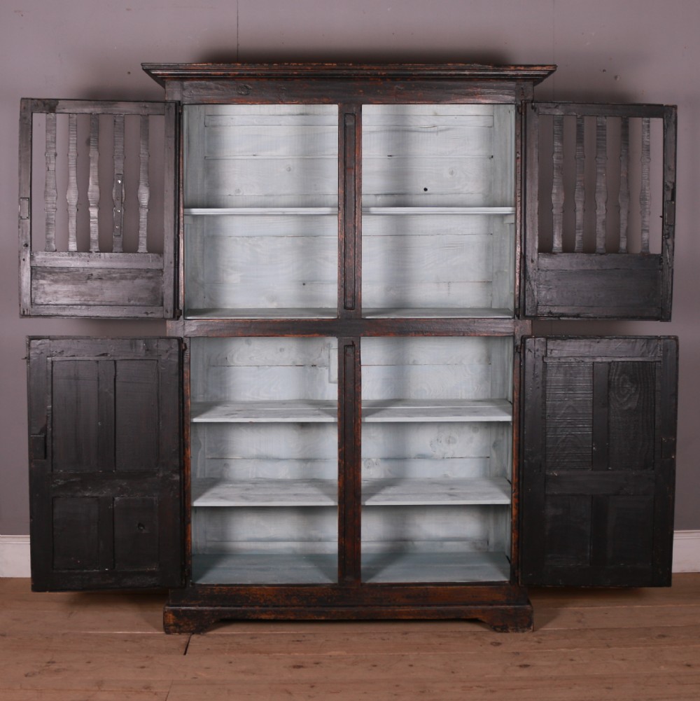 An 18th-century French dark oak food cupboard featuring turned spindle upper door panels and solid wooden lower door panels. View VIII