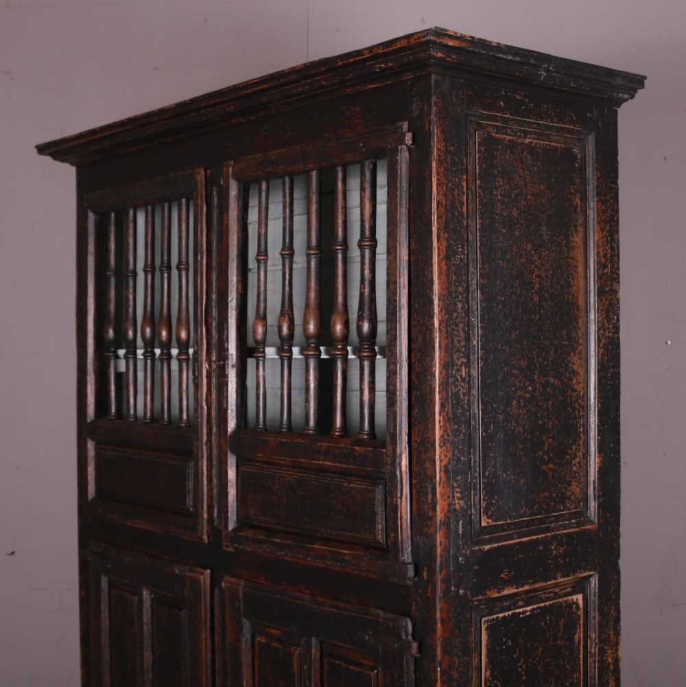 An 18th-century French dark oak food cupboard featuring turned spindle upper door panels and solid wooden lower door panels. View XI