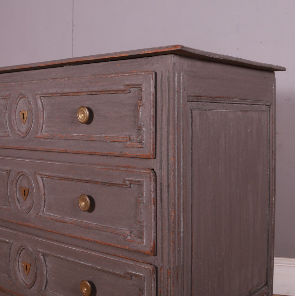 A French Neoclassical grey-painted three-drawer commode featuring geometric drawer moldings, brass hardware, and fluted legs. View III