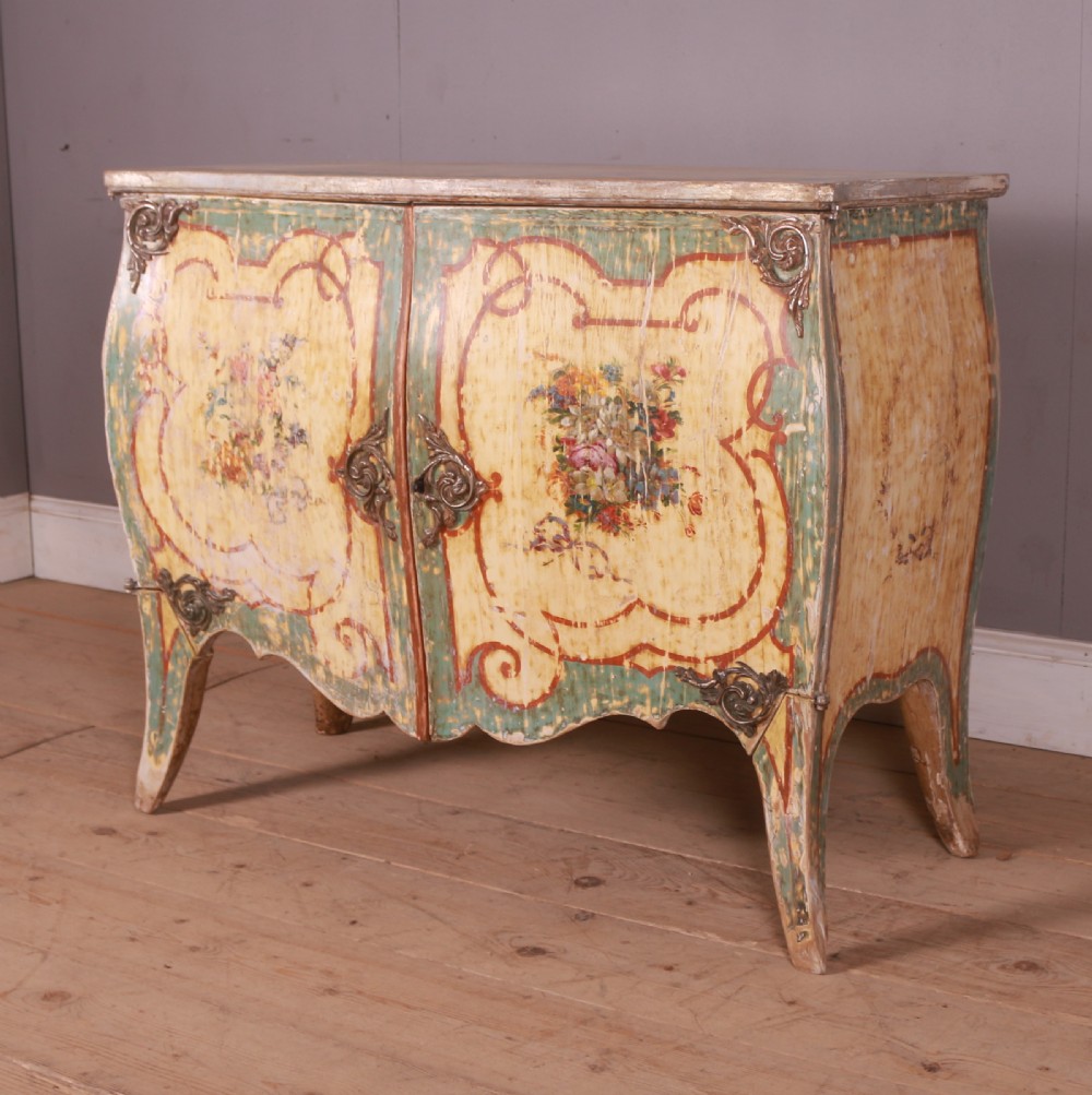 A Venetian serpentine painted wooden buffet cabinet featuring hand-painted floral cartouches, a polychrome green and cream finish, and metal corner mounts.