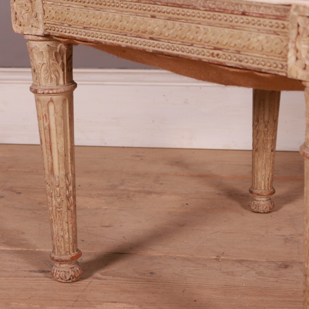 A square Swedish Gustavian upholstered stool featuring distressed cream painted wood legs with fluted carving and a light linen seat. View III