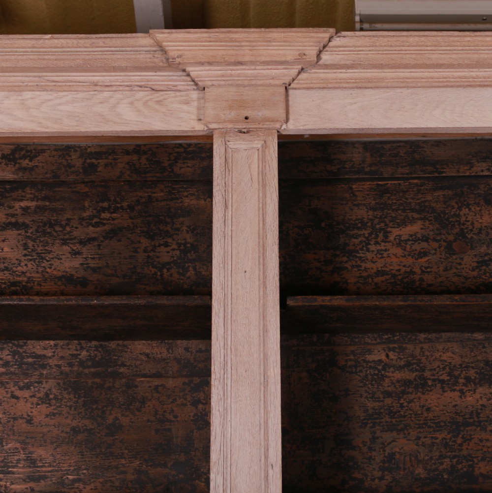An 18th-century French bleached oak bookcase featuring upper open shelving against dark backboards and a lower section with four fielded panel doors. View III