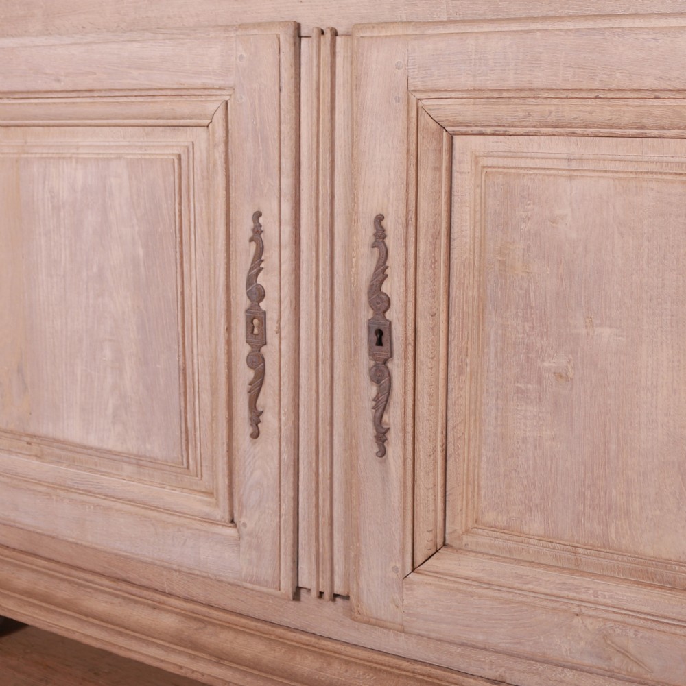 An 18th-century French bleached oak bookcase featuring upper open shelving against dark backboards and a lower section with four fielded panel doors. View VII