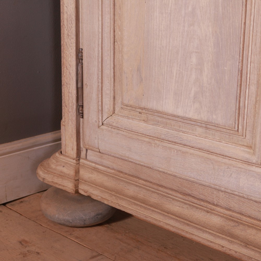 An 18th-century French bleached oak bookcase featuring upper open shelving against dark backboards and a lower section with four fielded panel doors. View VIII