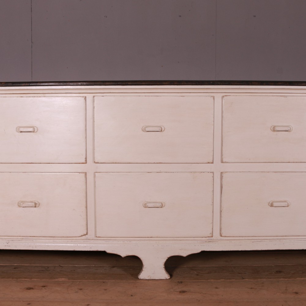A long off-white painted French bank of drapers drawers featuring ten large drawers with wooden handles and a dark stained top surface. View III