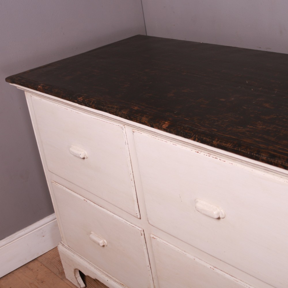 A long off-white painted French bank of drapers drawers featuring ten large drawers with wooden handles and a dark stained top surface. View VI