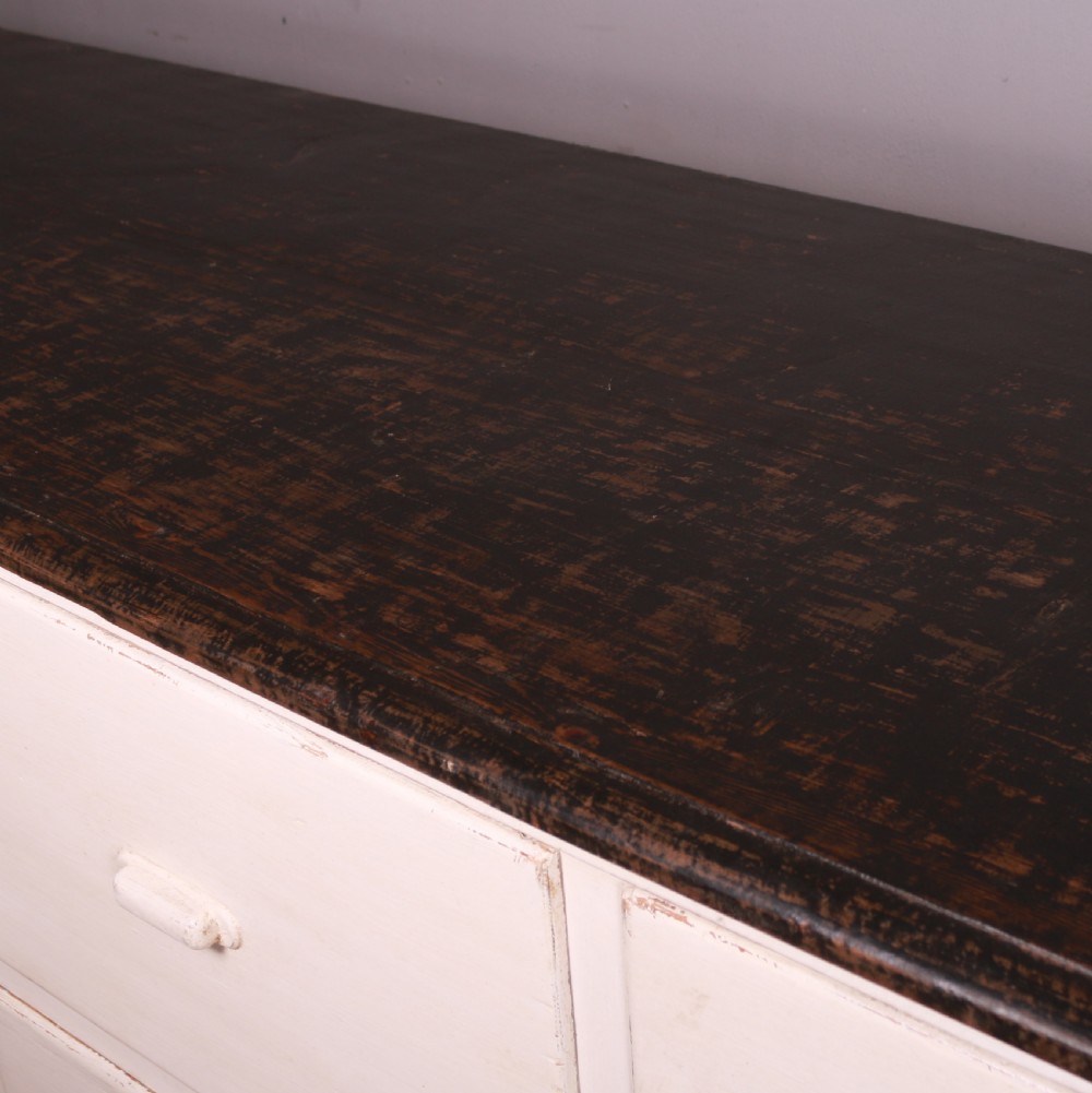A long off-white painted French bank of drapers drawers featuring ten large drawers with wooden handles and a dark stained top surface. View VIII