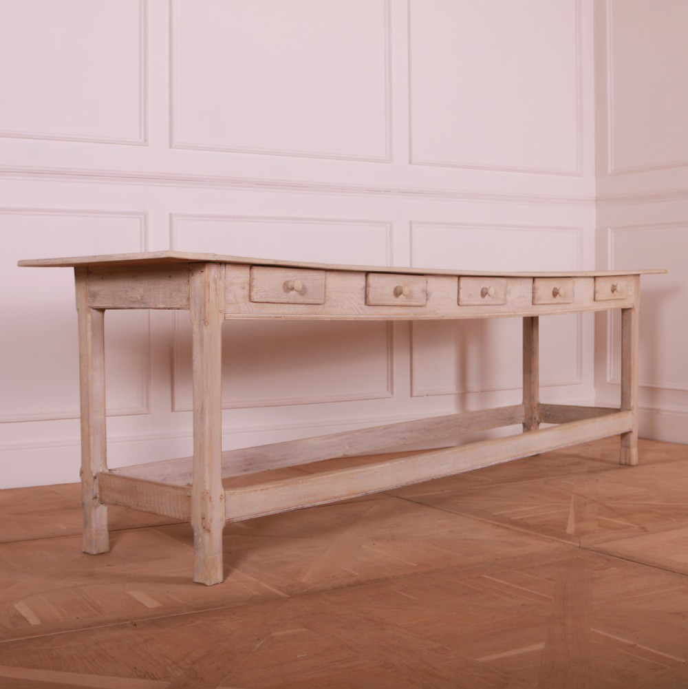 A long bleached oak serving table with five drawers, turned wooden knobs, square legs, and a low stretcher frame.
