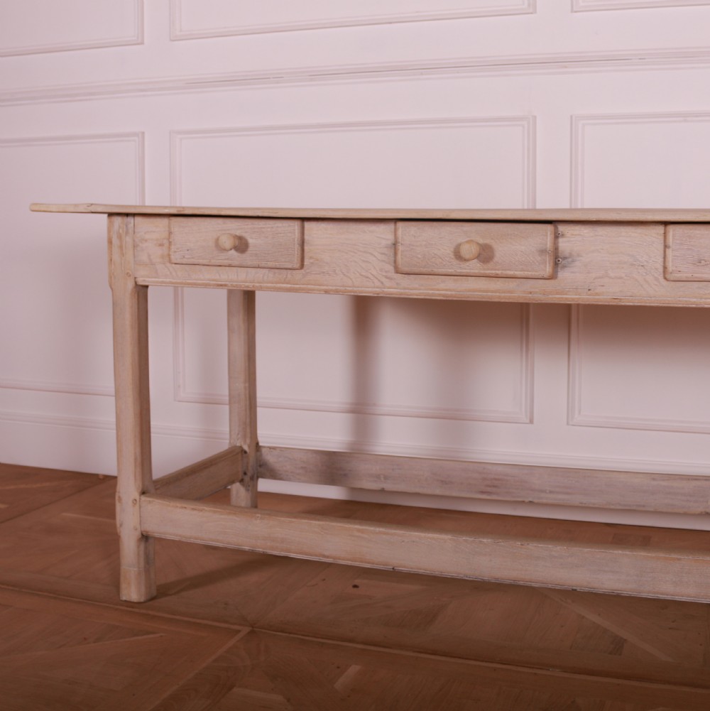A long bleached oak serving table with five drawers, turned wooden knobs, square legs, and a low stretcher frame. View III
