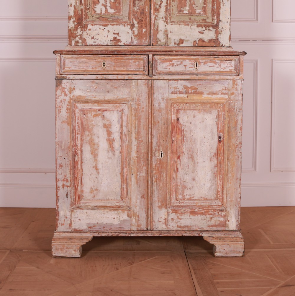 A tall Swedish pine linen cupboard featuring double panelled doors, two drawers, and a heavily scraped original cream paint finish. View II