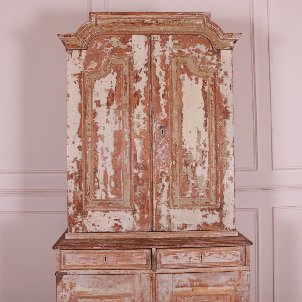 A tall Swedish pine linen cupboard featuring double panelled doors, two drawers, and a heavily scraped original cream paint finish. View III