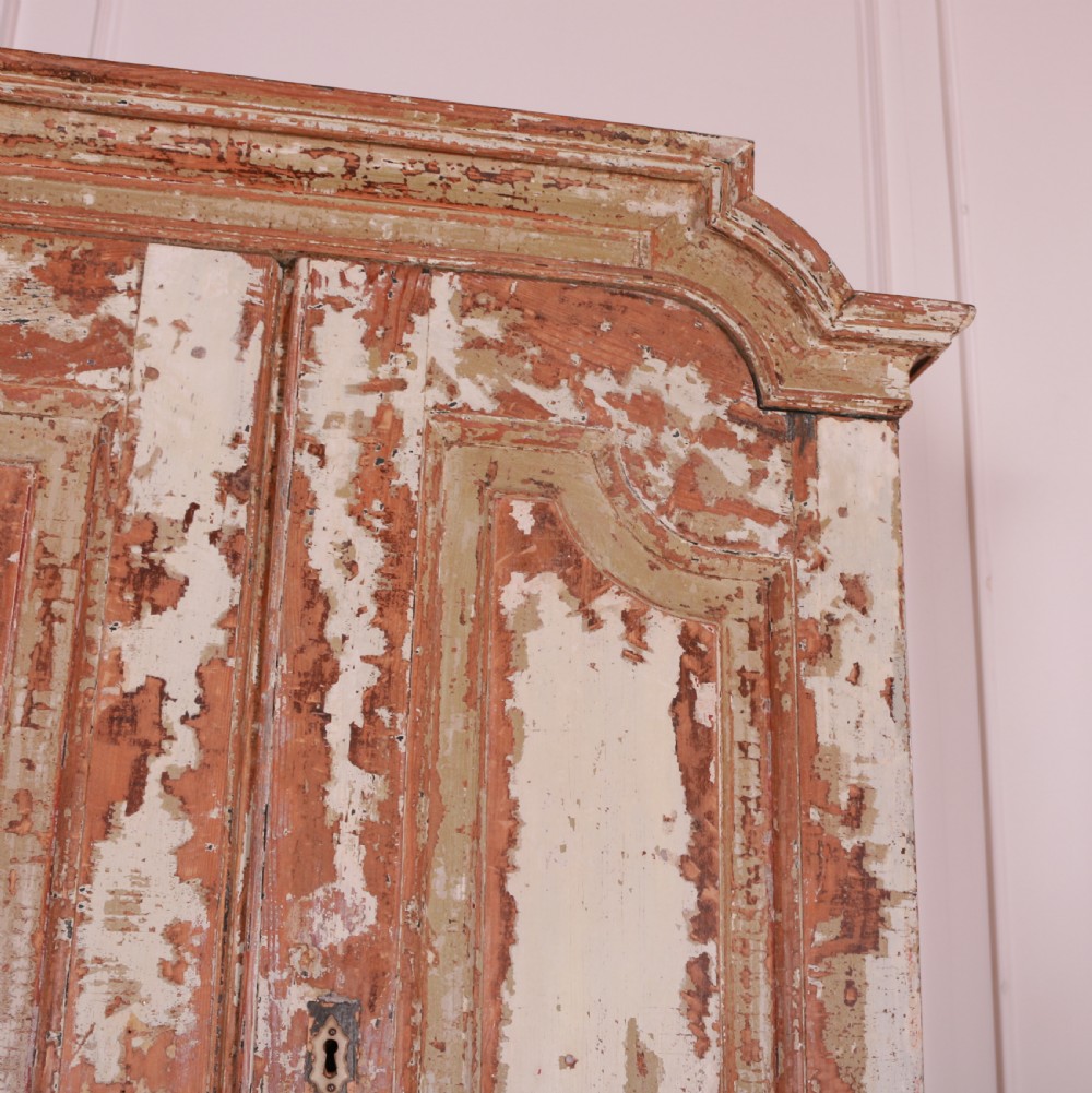 A tall Swedish pine linen cupboard featuring double panelled doors, two drawers, and a heavily scraped original cream paint finish. View V