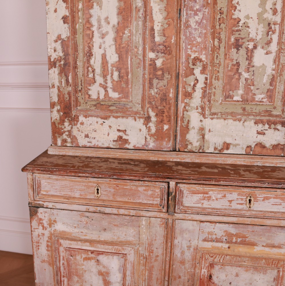 A tall Swedish pine linen cupboard featuring double panelled doors, two drawers, and a heavily scraped original cream paint finish. View VI