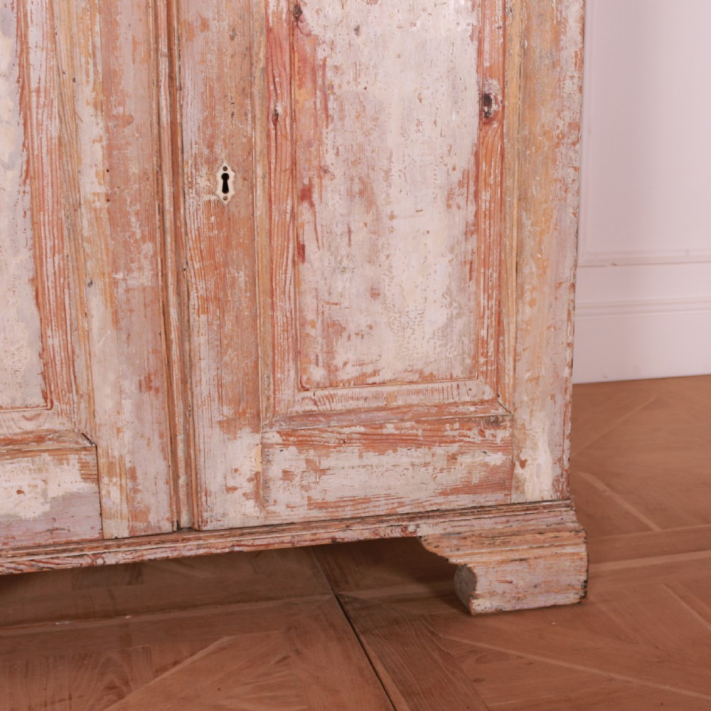 A tall Swedish pine linen cupboard featuring double panelled doors, two drawers, and a heavily scraped original cream paint finish. View VII