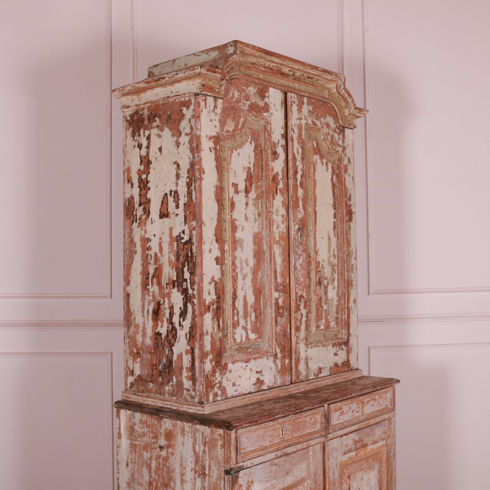 A tall Swedish pine linen cupboard featuring double panelled doors, two drawers, and a heavily scraped original cream paint finish. View IX
