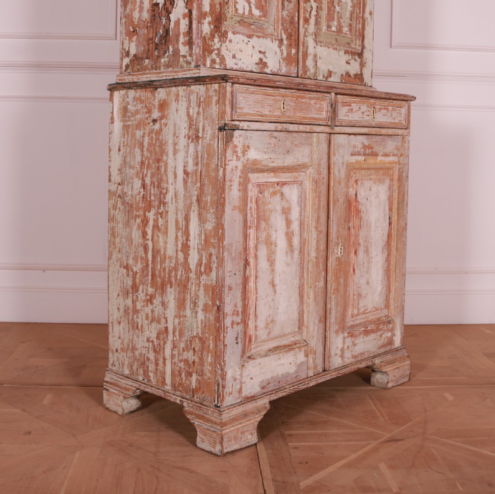 A tall Swedish pine linen cupboard featuring double panelled doors, two drawers, and a heavily scraped original cream paint finish. View X