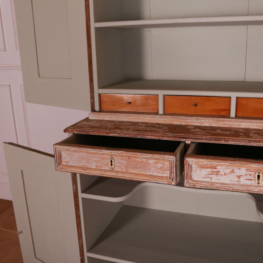 A tall Swedish pine linen cupboard featuring double panelled doors, two drawers, and a heavily scraped original cream paint finish. View XII