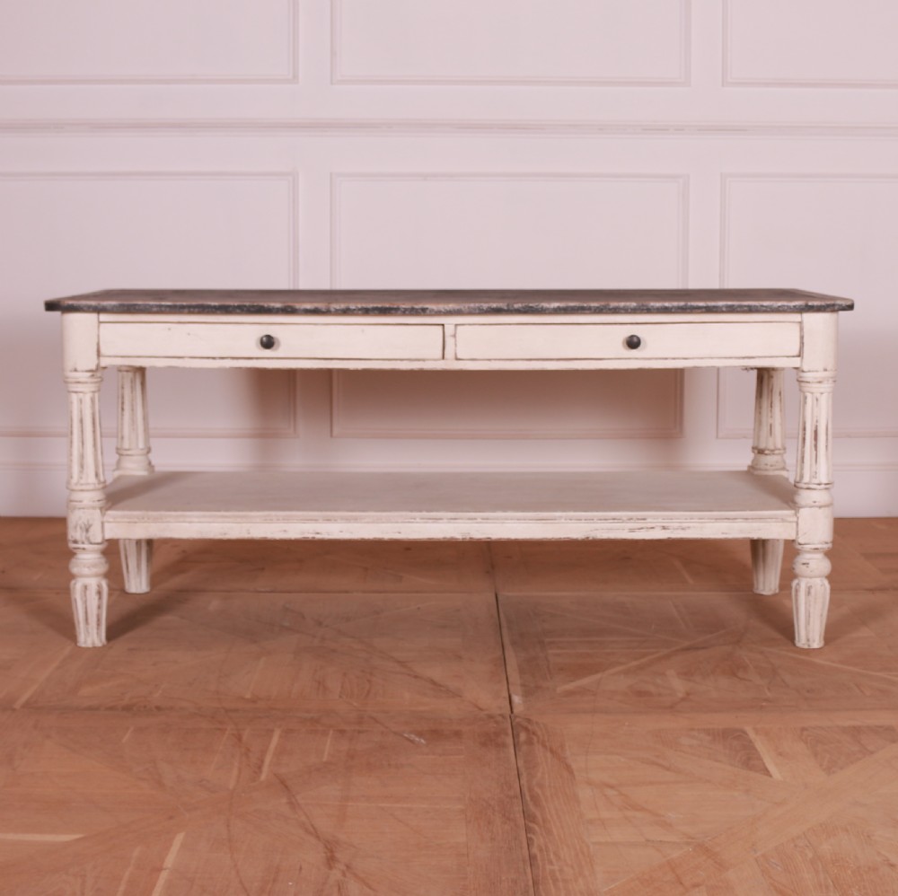 A cream painted pine side table featuring two drawers, turned fluted legs, a lower open shelf, and a dark contrasting top. View II