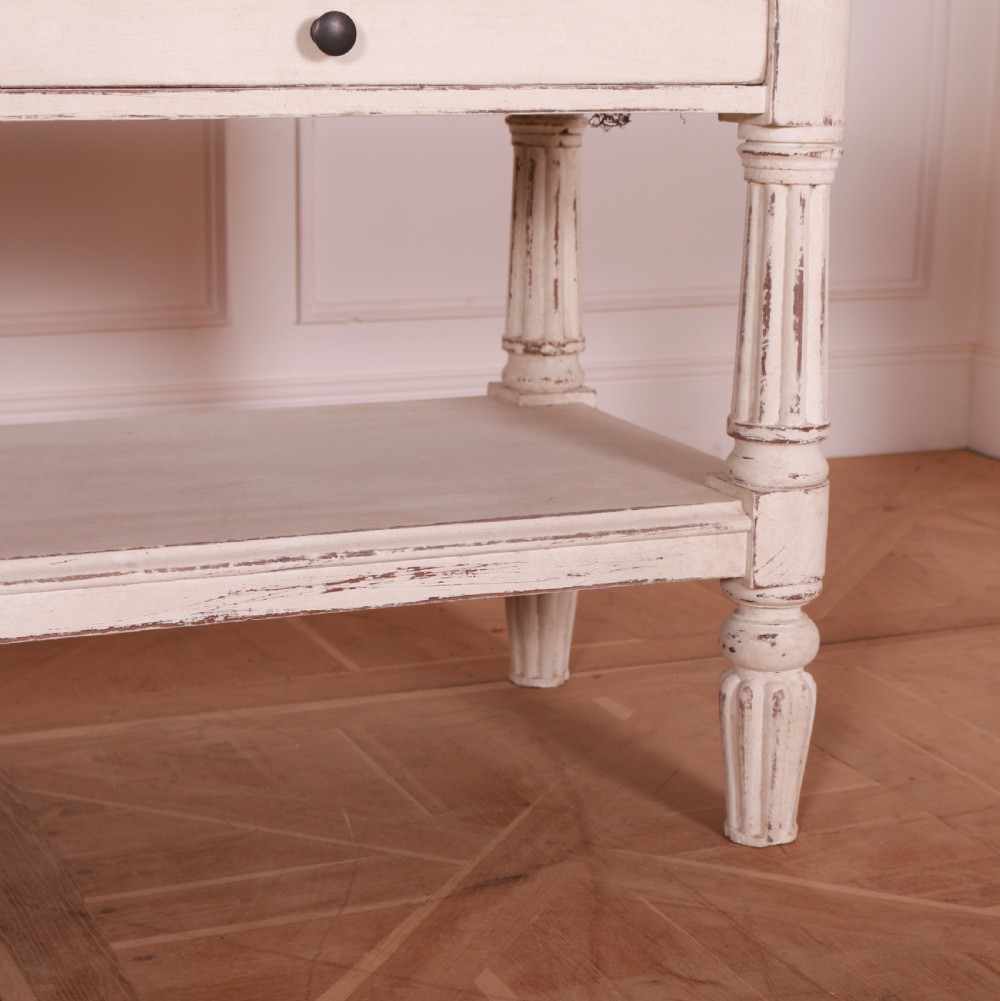 A cream painted pine side table featuring two drawers, turned fluted legs, a lower open shelf, and a dark contrasting top. View VI