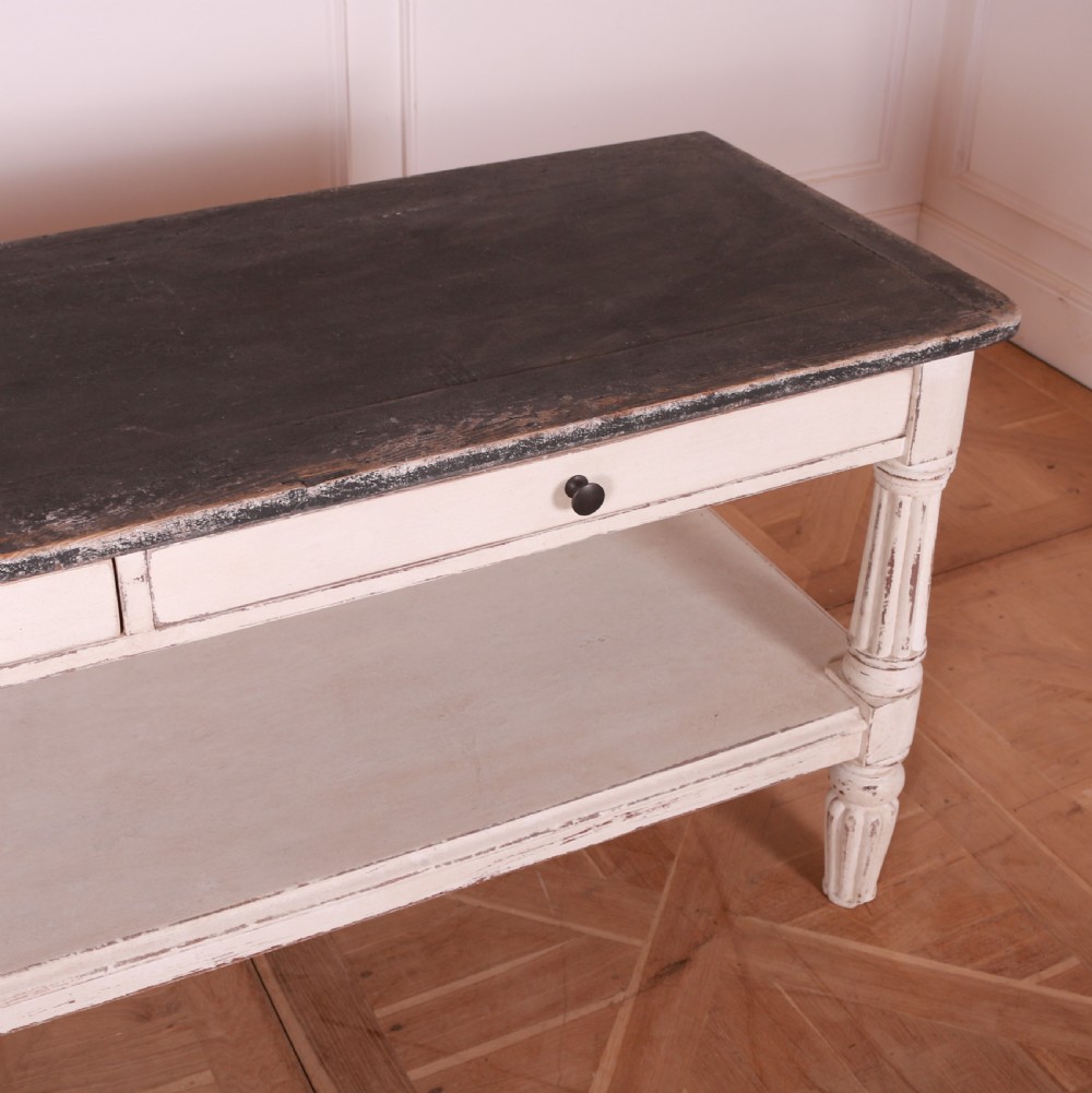 A cream painted pine side table featuring two drawers, turned fluted legs, a lower open shelf, and a dark contrasting top. View VIII