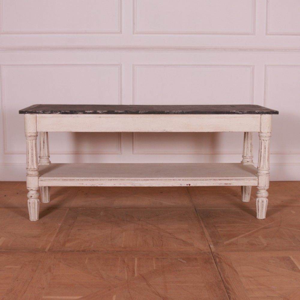 A cream painted pine side table featuring two drawers, turned fluted legs, a lower open shelf, and a dark contrasting top. View IX