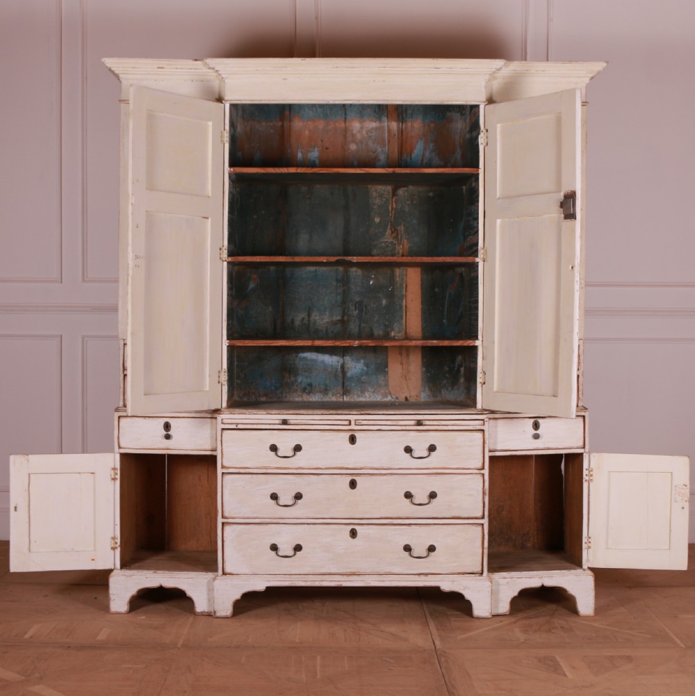 An eighteenth-century off-white painted housekeepers cupboard featuring fielded panel cupboard doors above multiple drawers with brass handles, supported by bracket feet. View XI